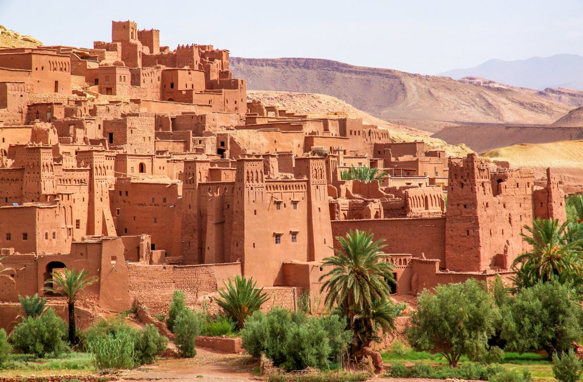 Kasbah d’Aït Ben Haddou – Trésor d’argile aux portes du désert marocain Vue sur la Kasbah d’Aït Ben Haddou, village en terre rouge typique du sud marocain, niché au cœur des palmeraies et des montagnes arides de l’Atlas.