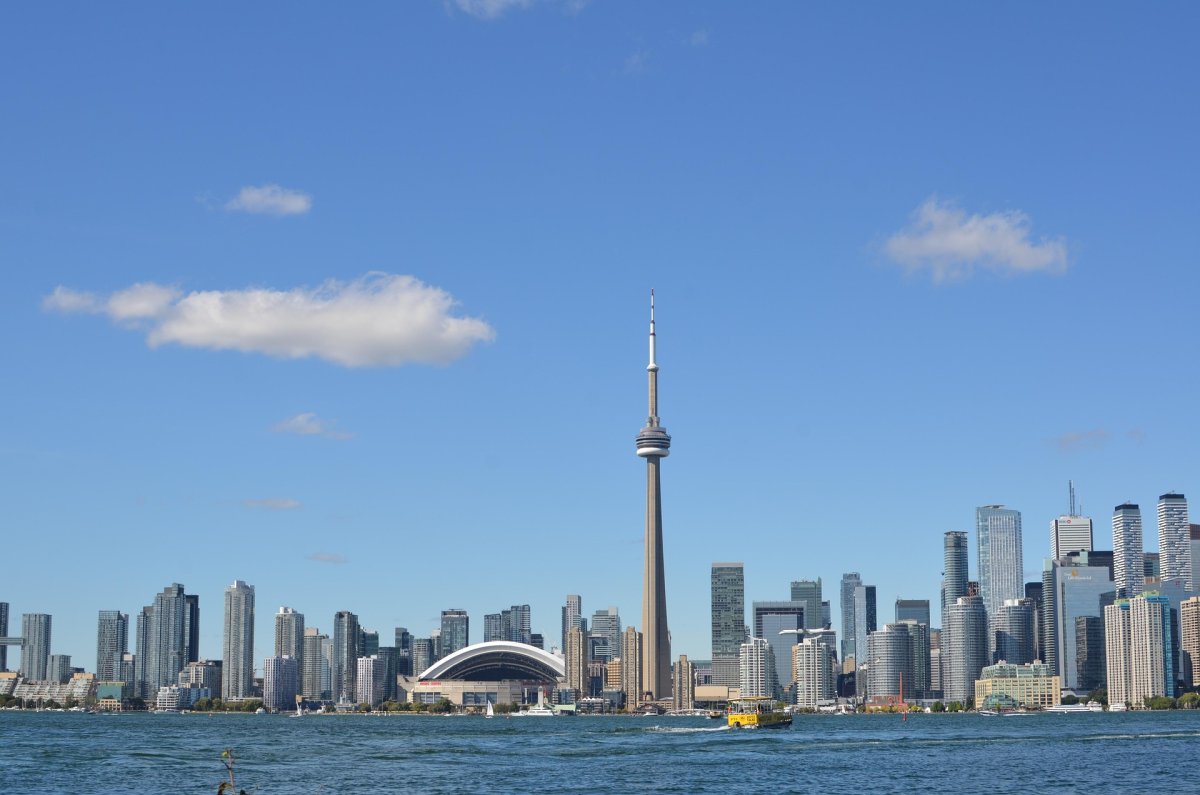 Toronto, entre modernité et horizon ouvert Vue panoramique sur la skyline de Toronto depuis les îles, avec la CN Tower dominant les gratte-ciels sous un ciel dégagé.